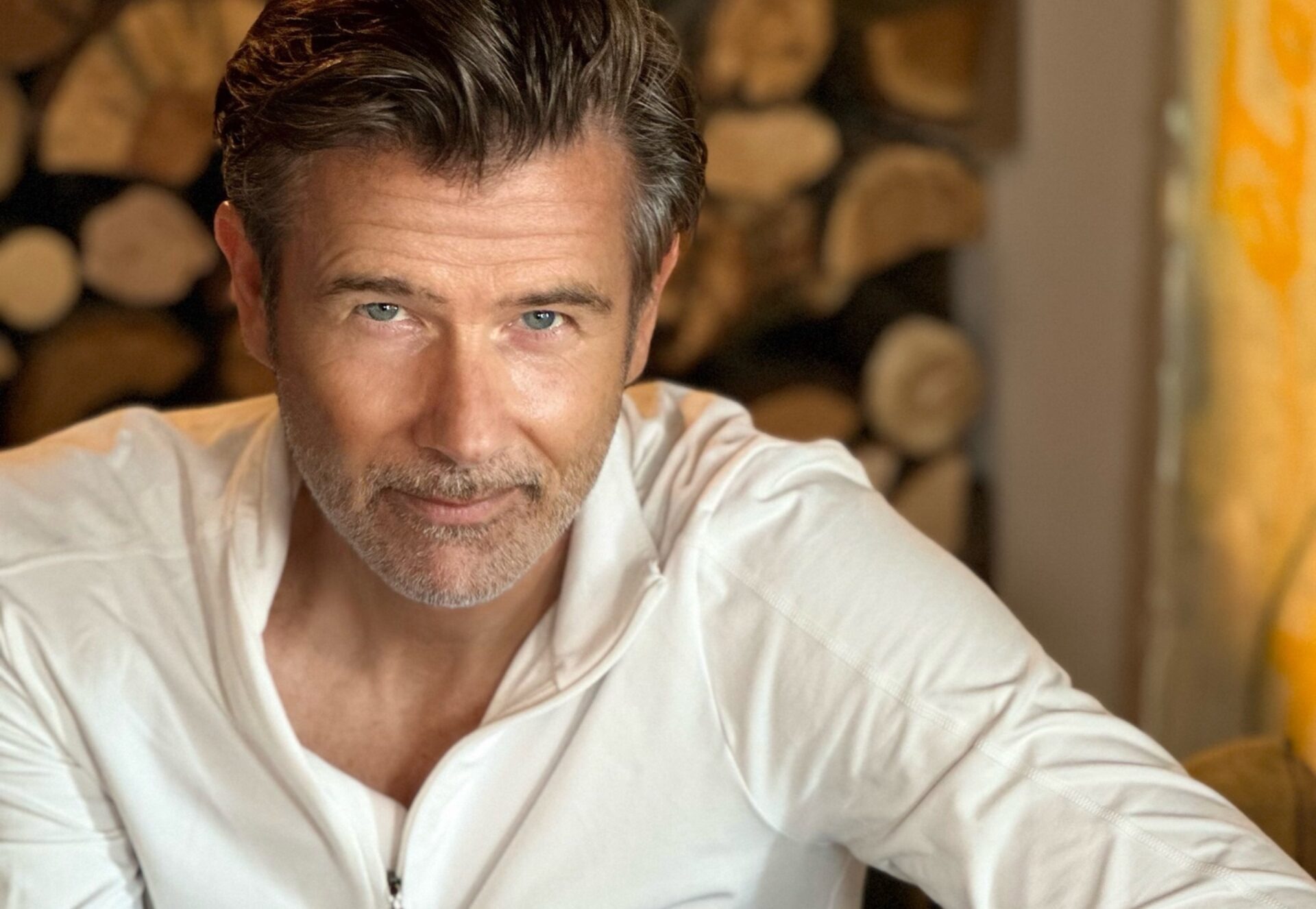 André Gebel, weißes Hemd, vor einem Holzstapel